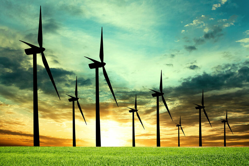 Fotografia przedstawia ustawione w polu wiatraki produkujące ekologiczną energię.
