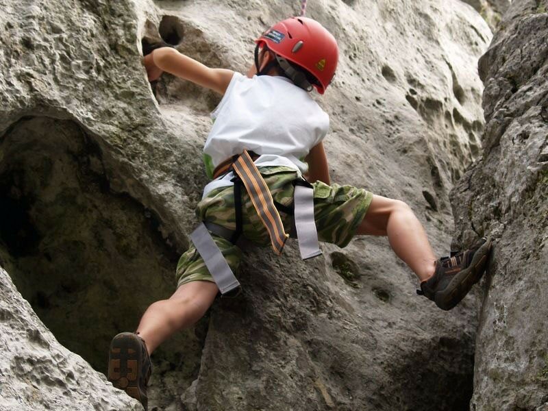 Ilustracja przedstawia chłopca w czerwonym kasku, który wspina się na skały.