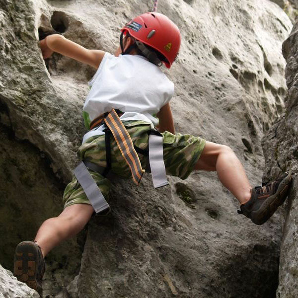 Ilustracja przedstawia chłopca w czerwonym kasku, który wspina się na skały.