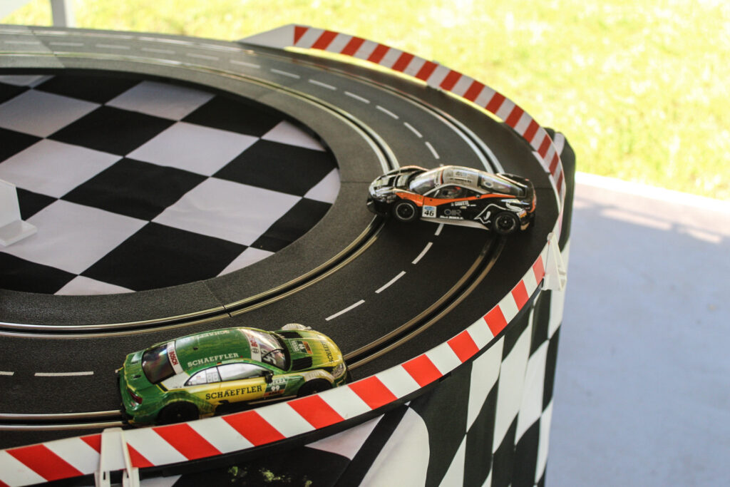 Na zdjęciu widoczny tor wyścigowy dla autek zabawkowych dla dzieci wraz z jeżdżącymi autkami. 