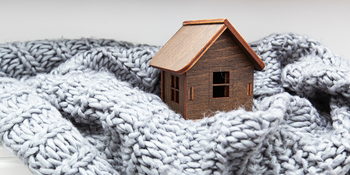 Obrazek przedstawia materiał, w którym znajduje się mały drewniany domek.