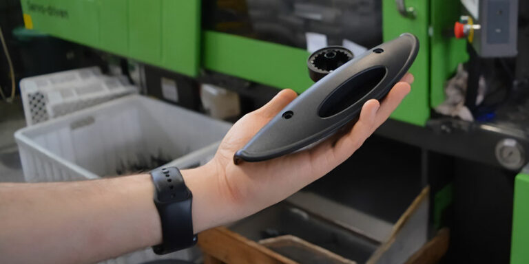 Na zdjęciu widać dłoń trzymającą niewielki, czarny element, wyprodukowany w firmie.