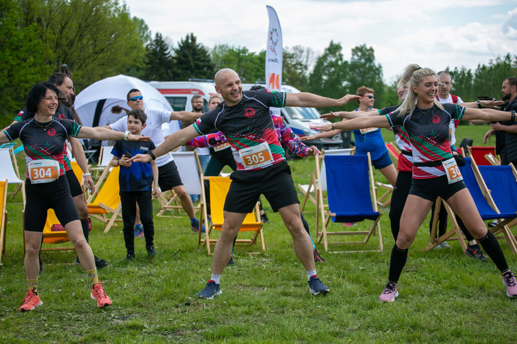 Zdjęcie przedstawia kilka osób stojących w rzędach, ubrane w strój do biegania, które uczestniczą w ćwiczeniach gimnastycznych. Fotografia pochodzą z archiwum Urzędu Marszałkowskiego Województwa Śląskiego.