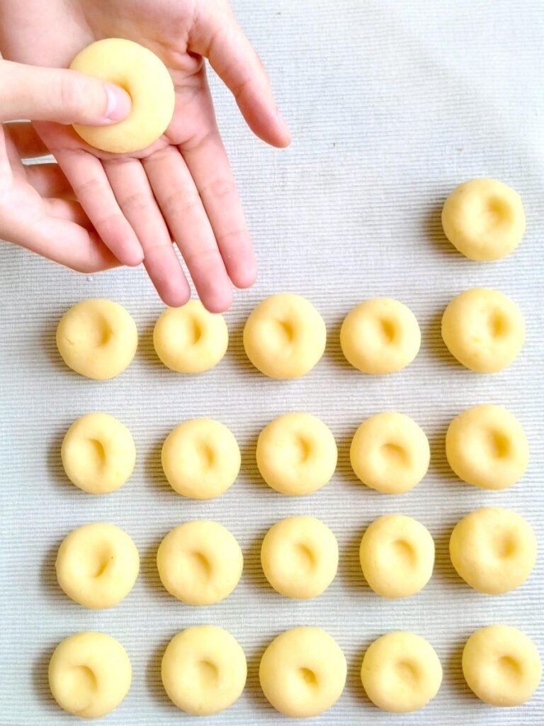 Dłonie formujące tradycyjne kluski śląskie. Zdjęcie odnosi się do Szlaku Kulinarnego „Śląskie Smaki” i promocji produktów regionalnych.